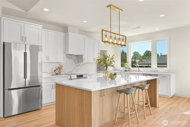 a kitchen with stainless steel appliances granite countertop a sink a stove a refrigerator and island with wooden floor