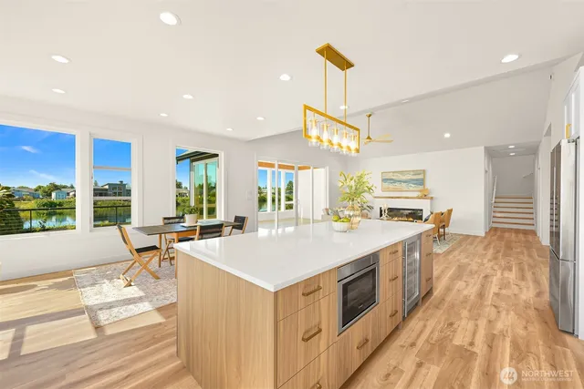 a large kitchen with kitchen island a large window a sink and a stove