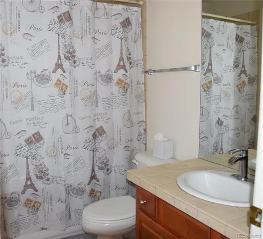 a bathroom with a granite countertop toilet sink and mirror