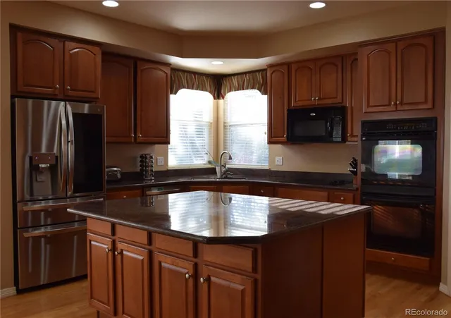 a kitchen with kitchen island granite countertop a sink stove and refrigerator