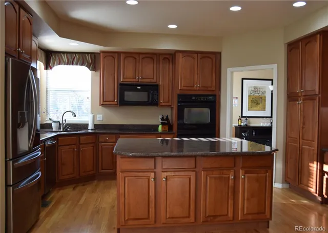 a kitchen with granite countertop a sink stove and refrigerator