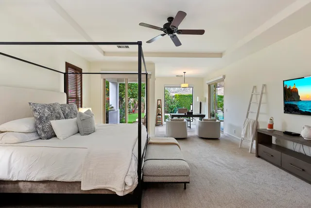 a bedroom with a bed a couch and a flat screen tv