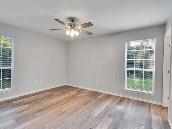 a view of empty room with wooden floor and fan