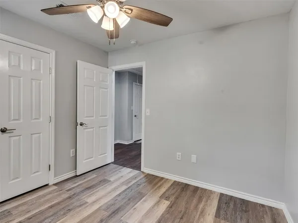 an empty room with wooden floor cabinet and windows