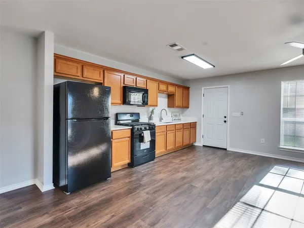 a kitchen with stainless steel appliances granite countertop a refrigerator a sink dishwasher a stove with white cabinets and wooden floor