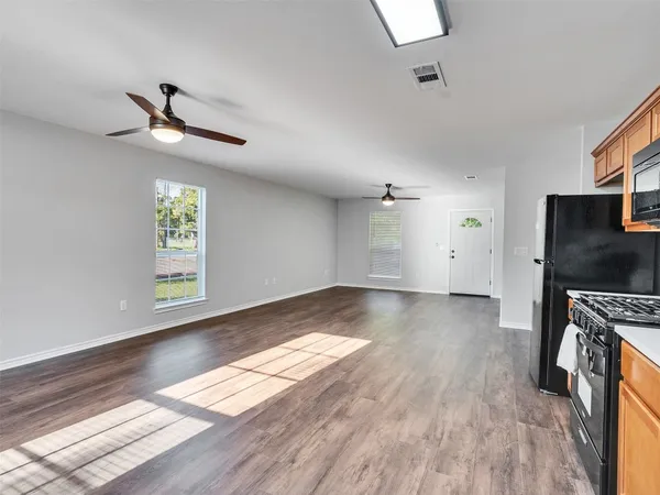 a view of empty room with wooden floor and fan