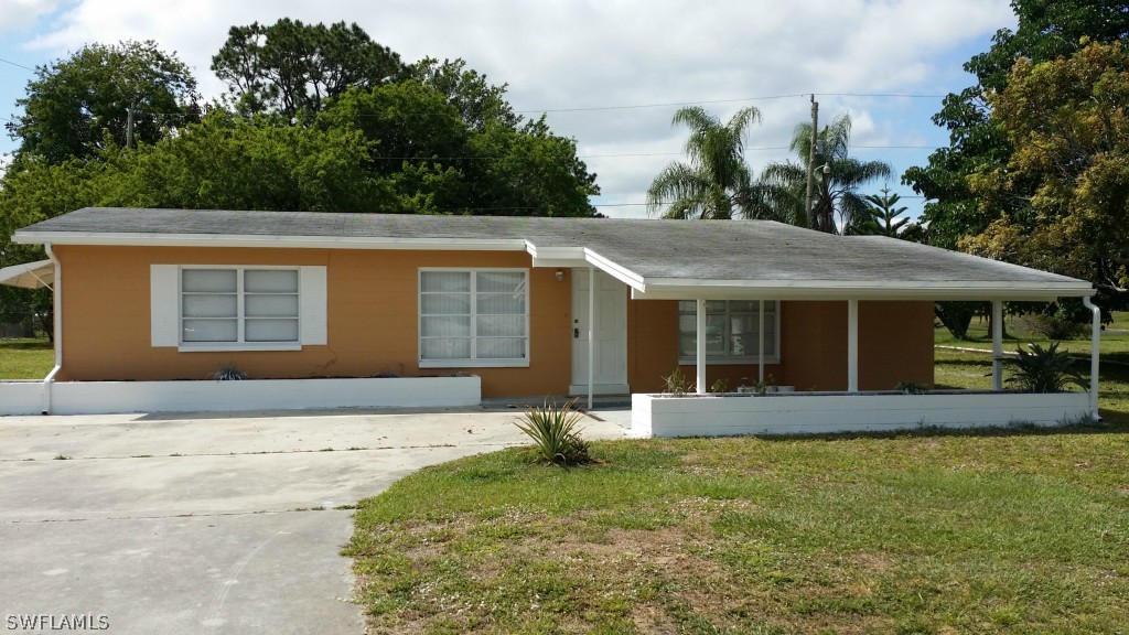 102 Jasmine Road West Lehigh Acres, FL 33936 - Photo 1 of 12 a front view of a house with a yard