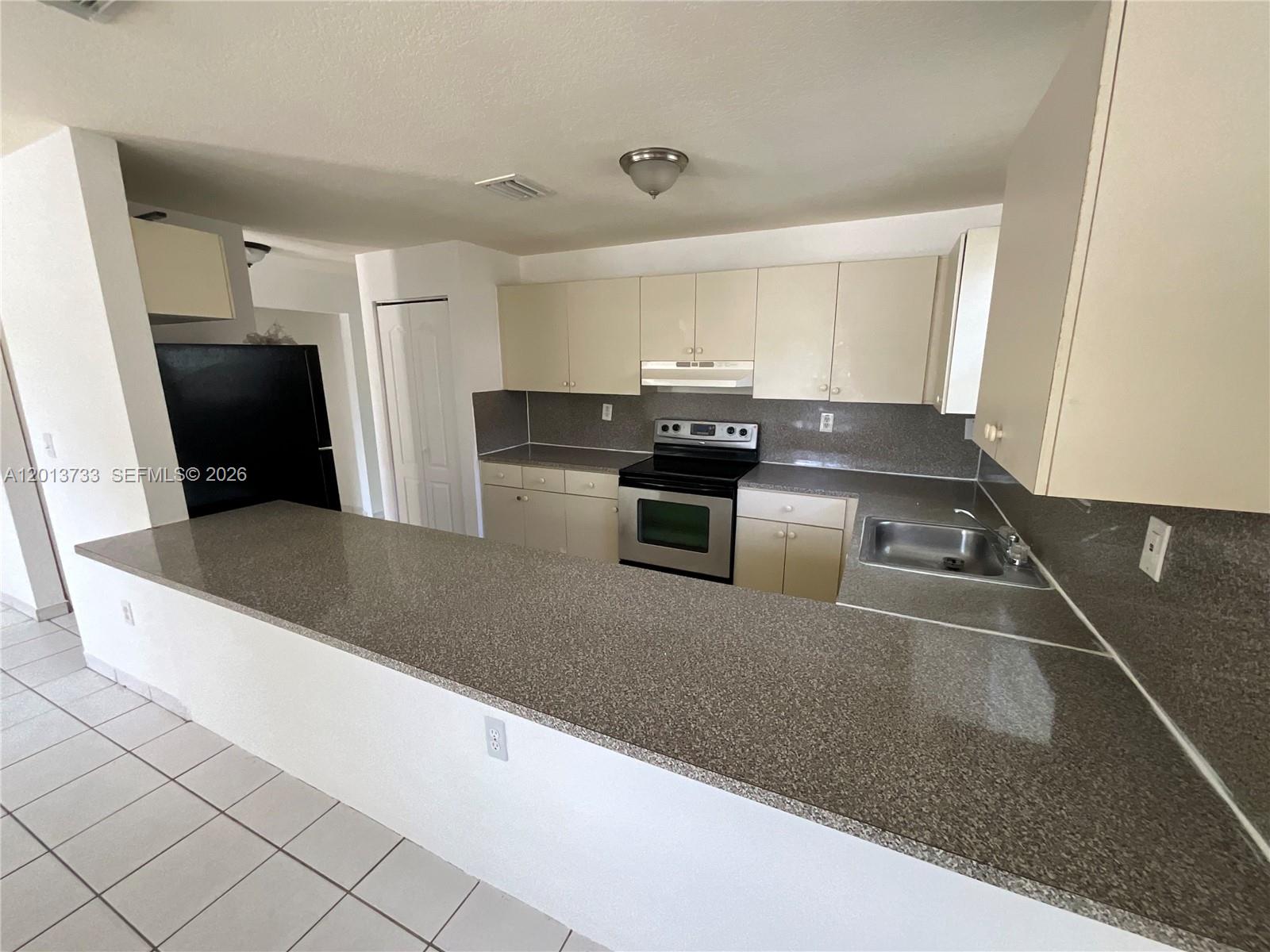 209 Northeast 141st Street, Unit 4 Miami, FL 33161 - Photo 4 of 13 a kitchen with stainless steel appliances granite countertop a sink a stove and a refrigerator