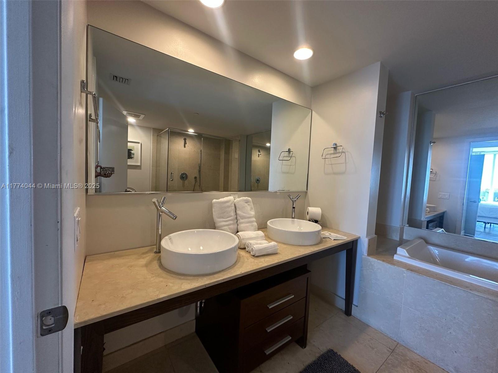 485 Brickell Avenue, Unit 4408 Miami, FL 33131 - Photo 14 of 15 a bathroom with a granite countertop sink a large mirror and a shower