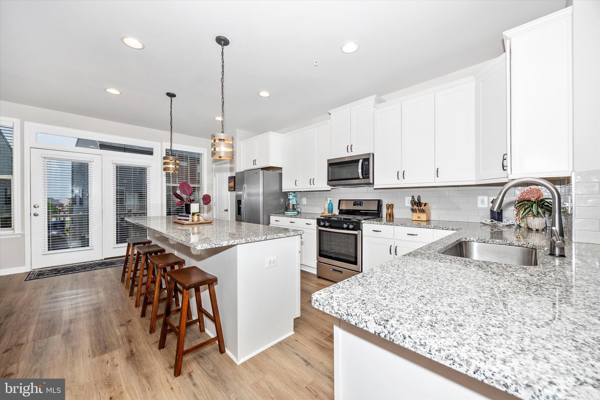 1817 Bird Run Frederick, MD 21702 - Photo 8 of 31 a kitchen with granite countertop a stove top oven a sink dishwasher a dining table and chairs with wooden floor