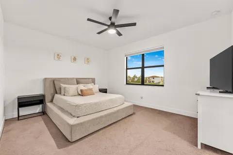 a bedroom with a bed a window and a flat screen tv