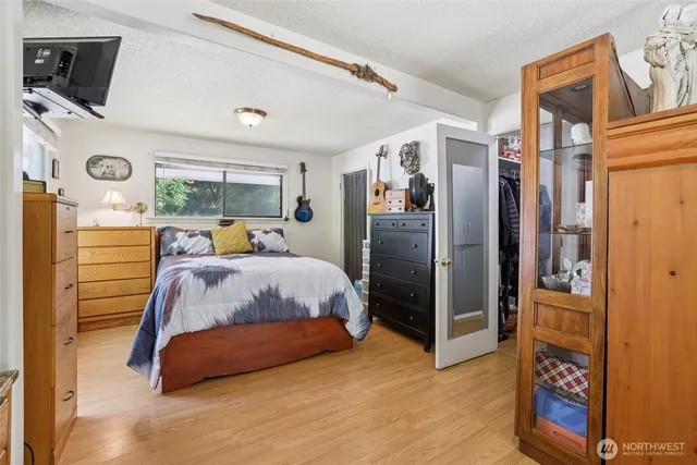 a bedroom with a bed dresser and a flat tv screen