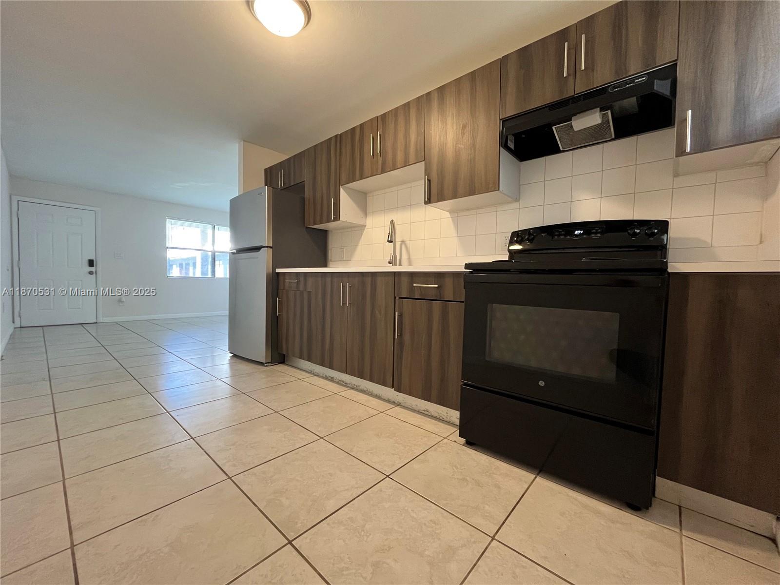 1610 North 25th Street, Unit 8 Fort Pierce, FL 34947 - Photo 4 of 7 a kitchen with granite countertop a stove and a wooden cabinets
