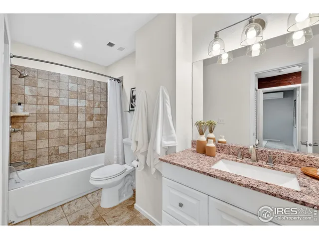 a bathroom with a granite countertop sink a toilet a mirror a bathtub and shower