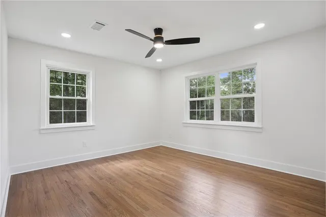 an empty room with wooden floor and windows