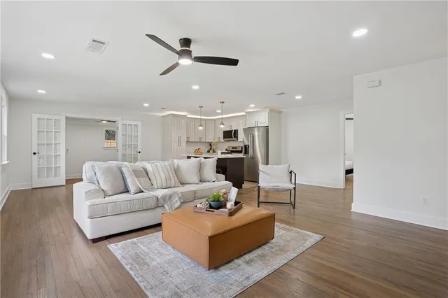 a living room with furniture kitchen area and a wooden floor