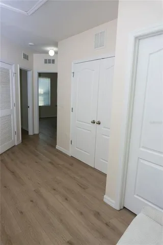 an empty room with wooden floor cabinet and windows