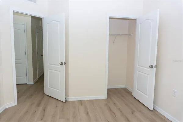 a view of an empty room with cabinet and mirrors