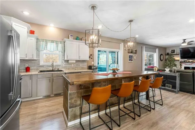a kitchen with stainless steel appliances granite countertop a sink a stove a refrigerator cabinets and chairs