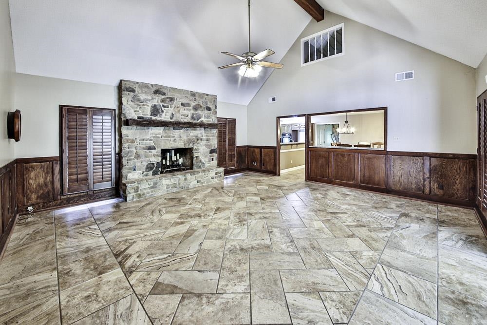 3693 Brunswick Road Bartlett, TN 38133 - Photo 15 of 30 Unfurnished living room with light tile patterned floors, ceiling fan with notable chandelier, beamed ceiling, a stone fireplace, and high vaulted ceiling