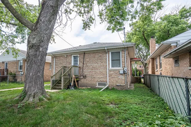 a view of a house with a yard and a large tree