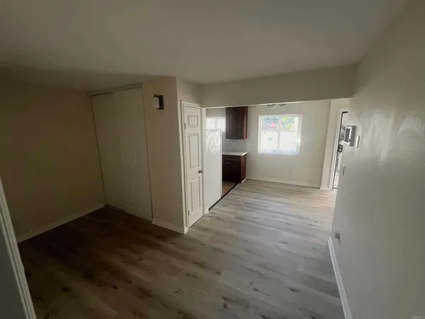 a view of an empty room with window and wooden floor