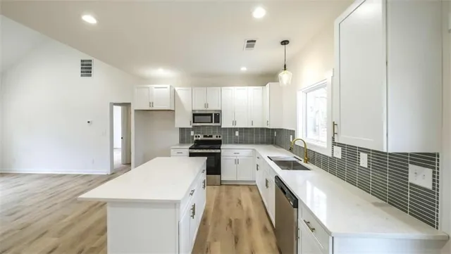 a kitchen with granite countertop a sink a counter top space stainless steel appliances and cabinets