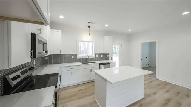 a kitchen with a sink stainless steel appliances and white cabinets