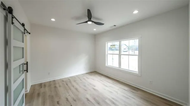 an empty room with wooden floor exposed radiator and windows