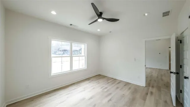 a view of empty room with wooden floor and fan