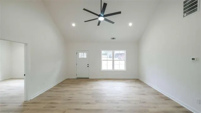 an empty room with wooden floor and windows