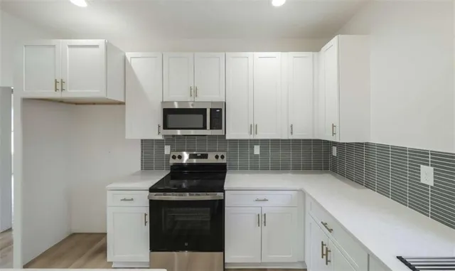 a kitchen with white cabinets and stainless steel appliances