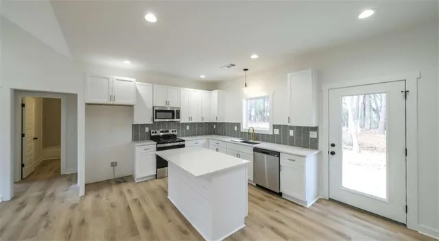 a kitchen with a sink a counter top space stainless steel appliances and cabinets