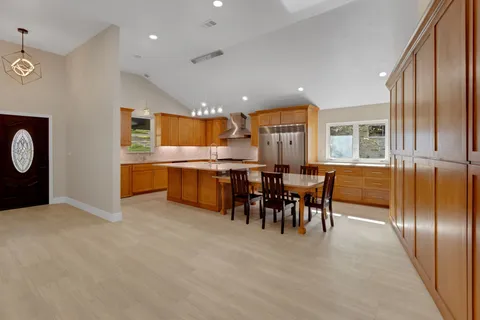 a kitchen with granite countertop a table chairs stainless steel appliances and cabinets