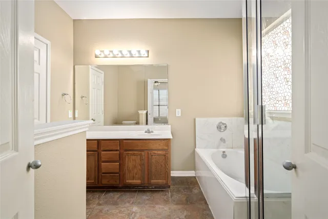 a spacious bathroom with a tub sink and mirror