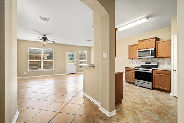 a large kitchen with kitchen island granite countertop a stove top oven a sink a counter space and cabinets
