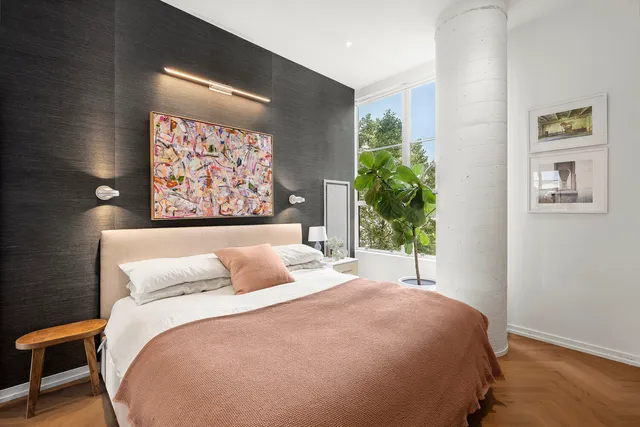 a bedroom with a bed and painting on the wall