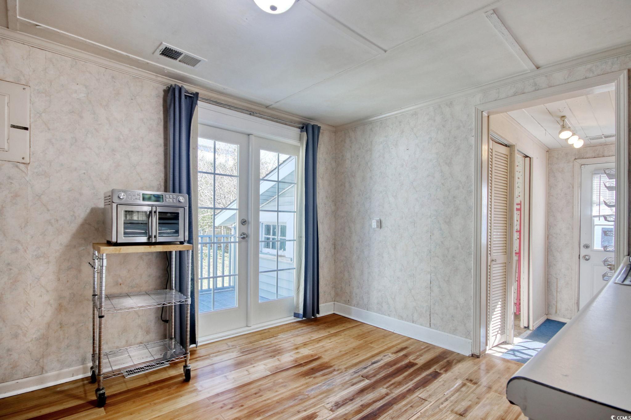 714 3rd Avenue South Surfside Beach, SC 29575 - Photo 11 of 30 Doorway with wallpapered walls, wood finished floors, french doors, plenty of natural light, and ornamental molding