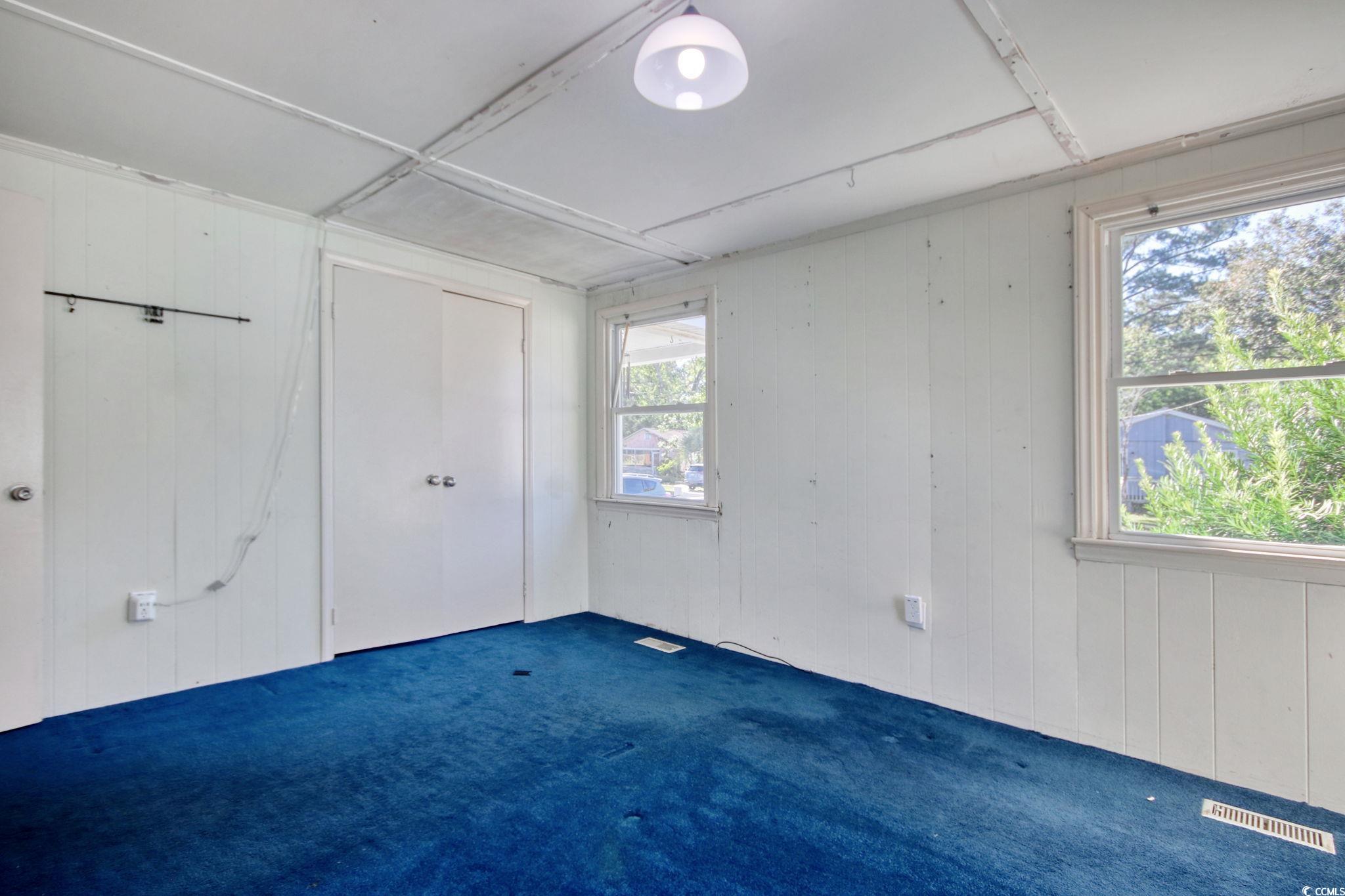 714 3rd Avenue South Surfside Beach, SC 29575 - Photo 15 of 30 Unfurnished bedroom featuring wooden walls, carpet floors, and a closet