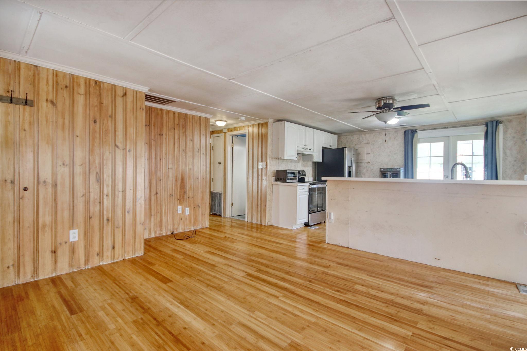 714 3rd Avenue South Surfside Beach, SC 29575 - Photo 6 of 30 Unfurnished living room featuring light wood-type flooring, a ceiling fan, and wood walls