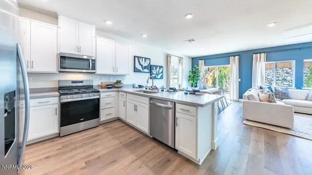 a kitchen with stainless steel appliances granite countertop a stove top oven a sink dishwasher a refrigerator and white cabinets with wooden floor