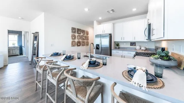 a kitchen with stainless steel appliances lots of white furniture refrigerator and wooden floor