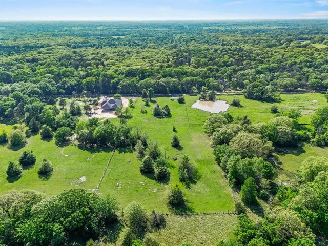 an aerial view of residential houses with outdoor space and trees