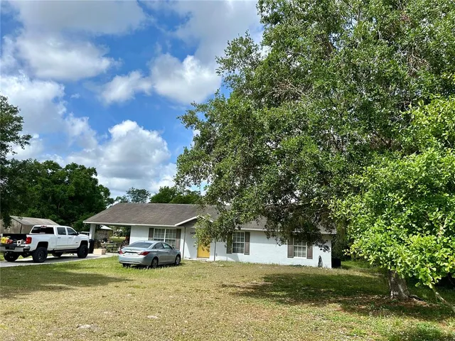 a front view of a house with a garden and trees