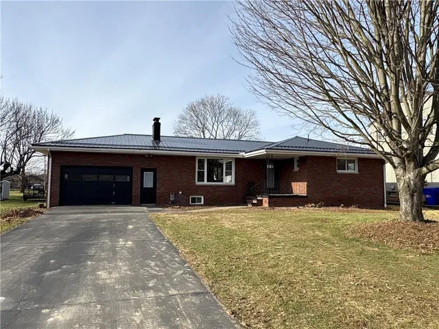 a view of a house with a yard and a large tree