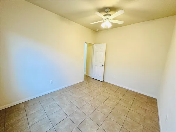an empty room with a ceiling fan and window