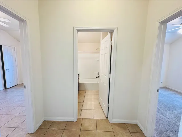 an empty room with a chandelier fan and windows