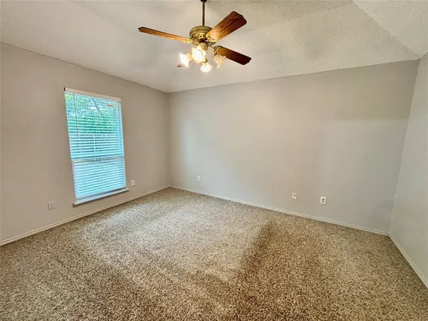 an empty room with windows and fan