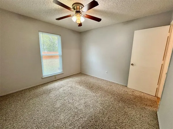 an empty room with a window and a fan
