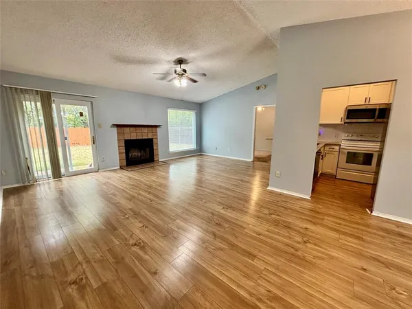 an empty room with wooden floor fireplace and windows